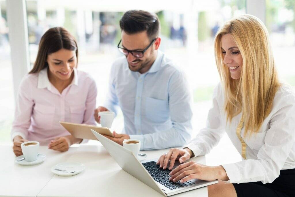 A team working in the office together on their gadgets with cups of coffee