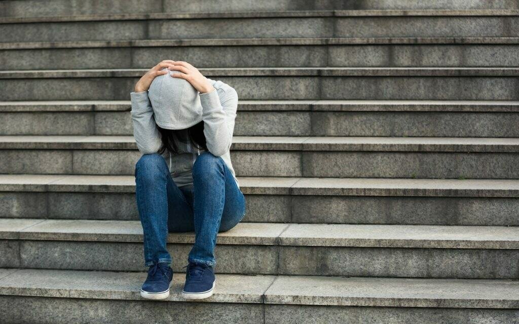 Depressed woman wearing hoodie sitting on the stairs