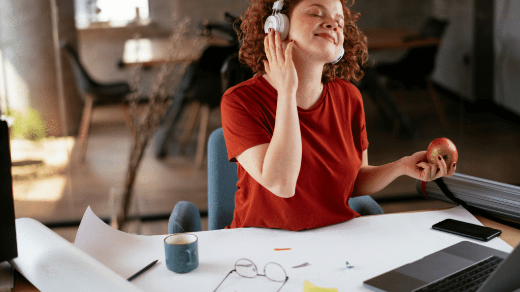 Woman enjoys the music playing on her headphones while working